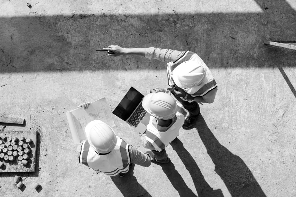 Vue aérienne équipe ingénieurs sur chantier avec plans de construction